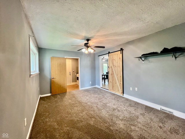 2833 Desoto Way, Columbus, IN 47203 - unfurnished bedroom featuring baseboards, a barn door, carpet flooring, a textured ceiling, and a ceiling fan