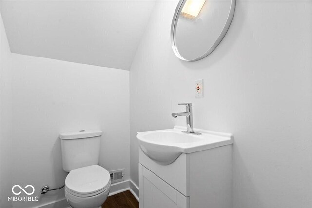 1709 Fletcher Ave, Indianapolis, IN 46203 - bathroom featuring vanity, toilet, vaulted ceiling, and wood finished floors