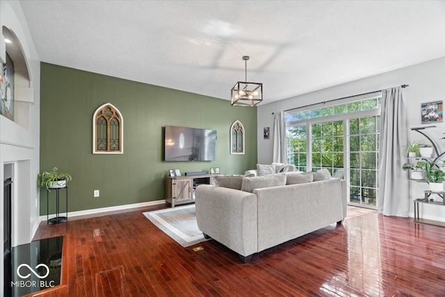 11509 Reagan Dr, Fishers, IN 46038 - living room featuring dark wood-type flooring, a chandelier, baseboards, and a fireplace