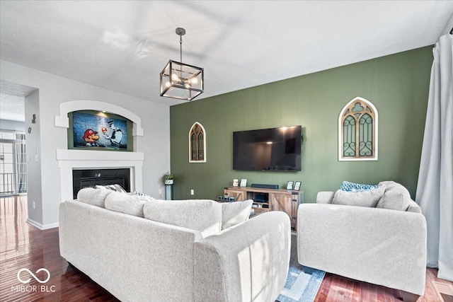 11509 Reagan Dr, Fishers, IN 46038 - living room featuring a glass covered fireplace, dark wood-type flooring, a chandelier, and baseboards