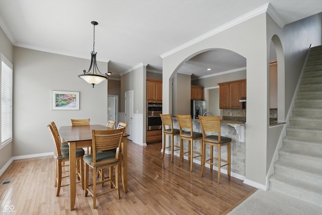 16802 Oak Manor Dr, Westfield, IN 46074 - dining room featuring light wood-style flooring, baseboards, stairs, crown molding, and arched walkways