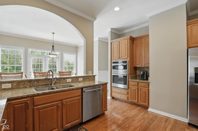 16802 Oak Manor Dr, Westfield, IN 46074 - kitchen featuring stainless steel appliances, a sink, light wood-type flooring, arched walkways, and light stone counters