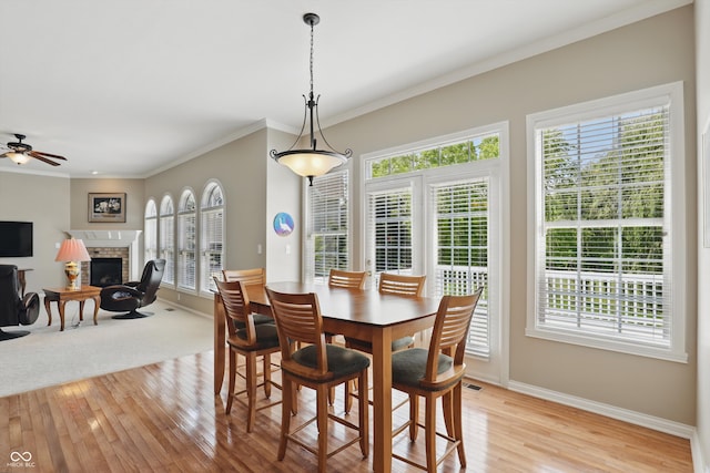 16802 Oak Manor Dr, Westfield, IN 46074 - dining space featuring light wood-style flooring, a fireplace, baseboards, ceiling fan, and ornamental molding