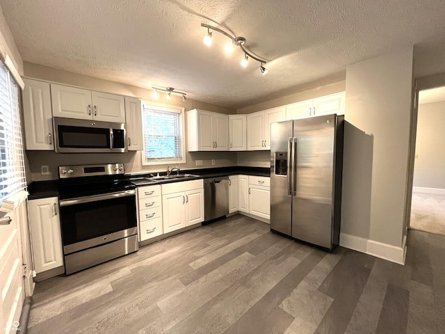 38 N Irvington Ave, Indianapolis, IN 46219 - kitchen featuring stainless steel appliances, dark countertops, a textured ceiling, white cabinetry, and wood finished floors