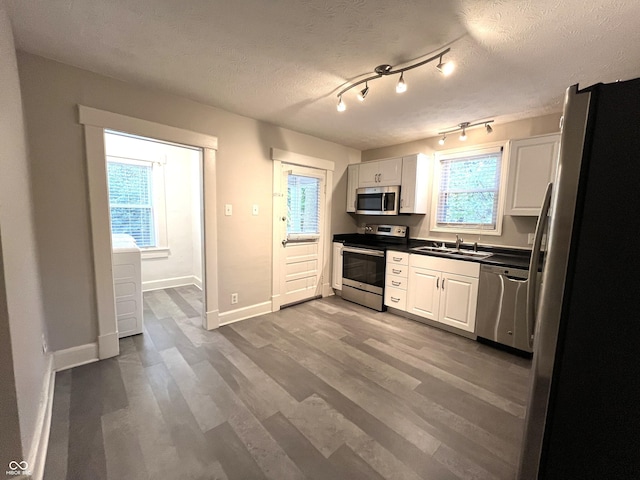 38 N Irvington Ave, Indianapolis, IN 46219 - kitchen featuring appliances with stainless steel finishes, dark countertops, white cabinetry, wood finished floors, and a textured ceiling