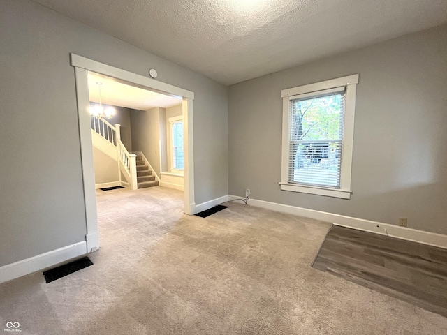 38 N Irvington Ave, Indianapolis, IN 46219 - carpeted empty room with stairs, a textured ceiling, and a chandelier