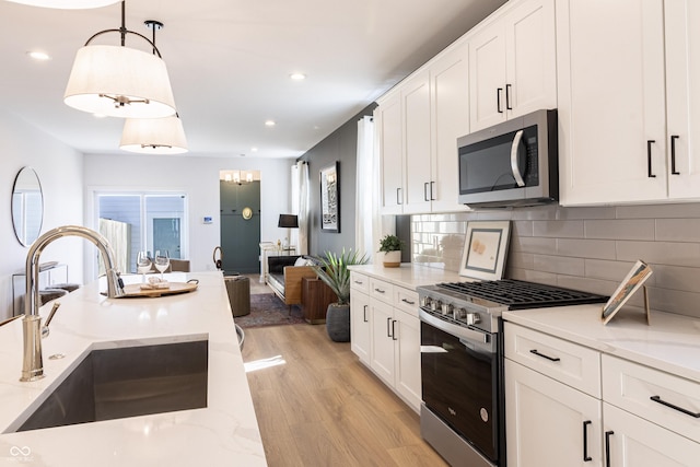 2051 Columbia Ave, Indianapolis, IN 46202 - kitchen with stainless steel appliances, a sink, light wood-style flooring, white cabinetry, and recessed lighting