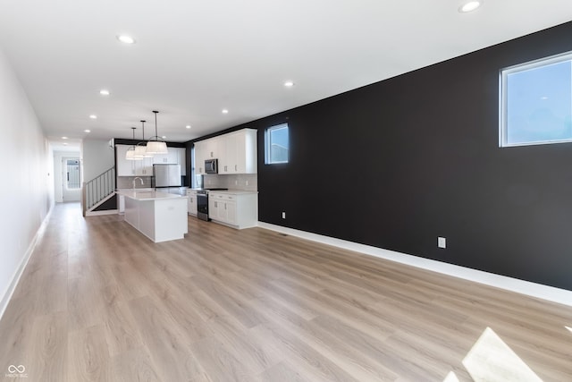 2053 Columbia Ave, Indianapolis, IN 46202 - kitchen with appliances with stainless steel finishes, open floor plan, light countertops, a center island with sink, and white cabinetry