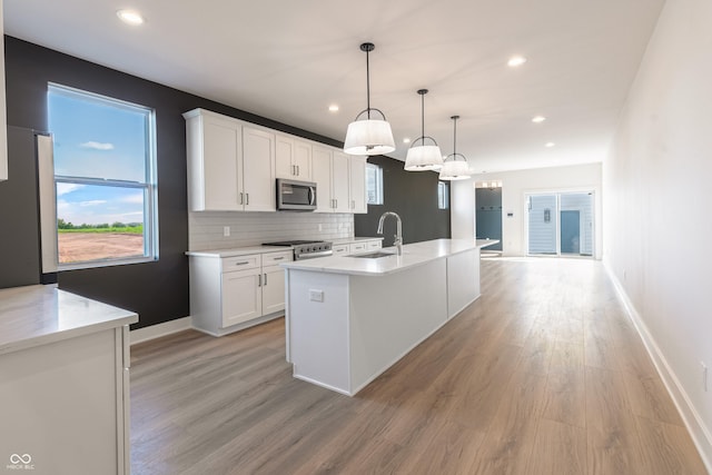 2053 Columbia Ave, Indianapolis, IN 46202 - kitchen with appliances with stainless steel finishes, a sink, light wood finished floors, white cabinets, and recessed lighting