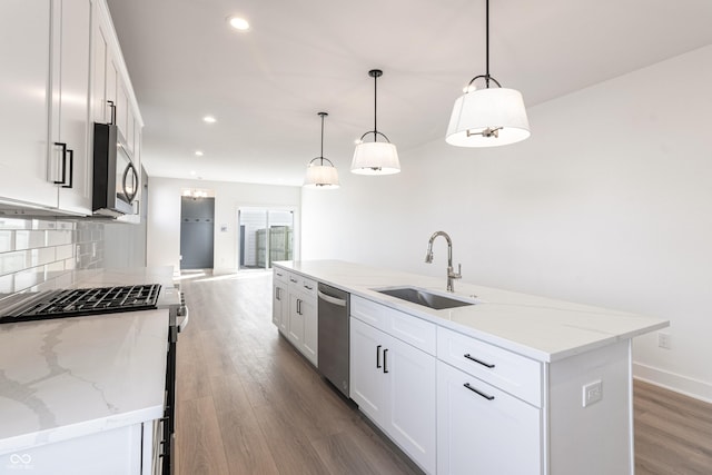 2053 Columbia Ave, Indianapolis, IN 46202 - kitchen with a sink, stainless steel appliances, wood finished floors, white cabinets, and backsplash