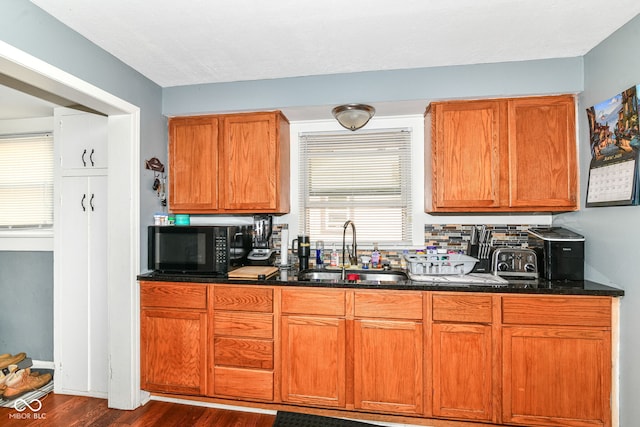 1619 E Bradbury Ave, Indianapolis, IN 46203 - kitchen featuring a sink, black microwave, dark wood finished floors, dark stone countertops, and brown cabinetry