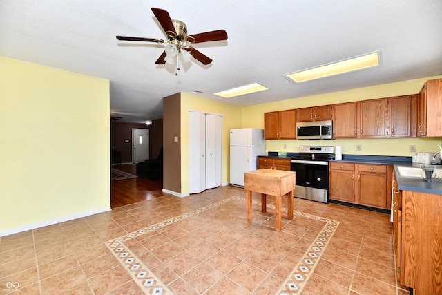 3429 Pavetto Ln, Indianapolis, IN 46203 - kitchen with stainless steel appliances, brown cabinets, dark countertops, light tile patterned floors, and a ceiling fan