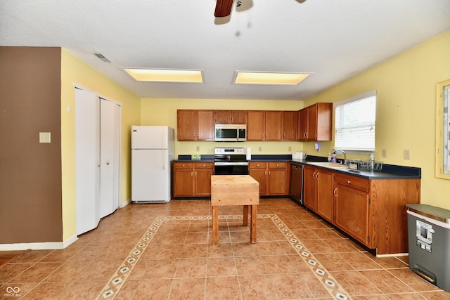 3429 Pavetto Ln, Indianapolis, IN 46203 - kitchen with appliances with stainless steel finishes, dark countertops, light tile patterned flooring, ceiling fan, and brown cabinetry