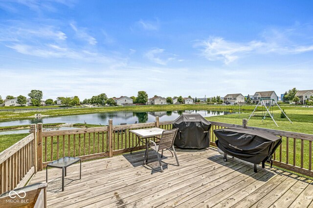 deck featuring a water view, a lawn, area for grilling, a residential view, and a playground