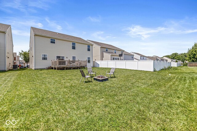 rear view of property featuring a fire pit, a wooden deck, central AC unit, and a residential view
