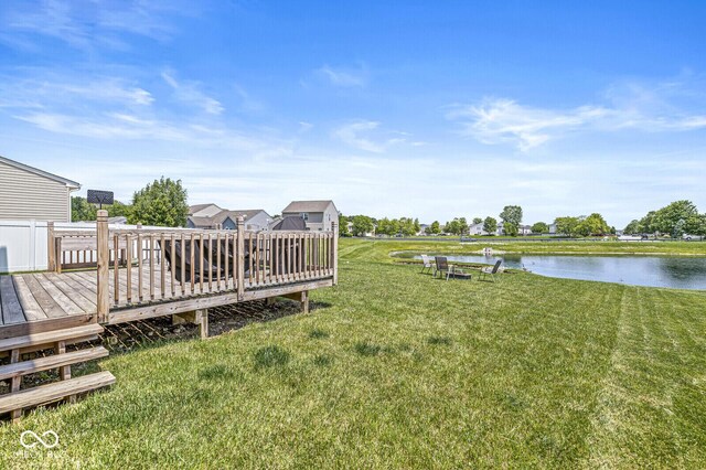 view of green lawn with a deck with water view