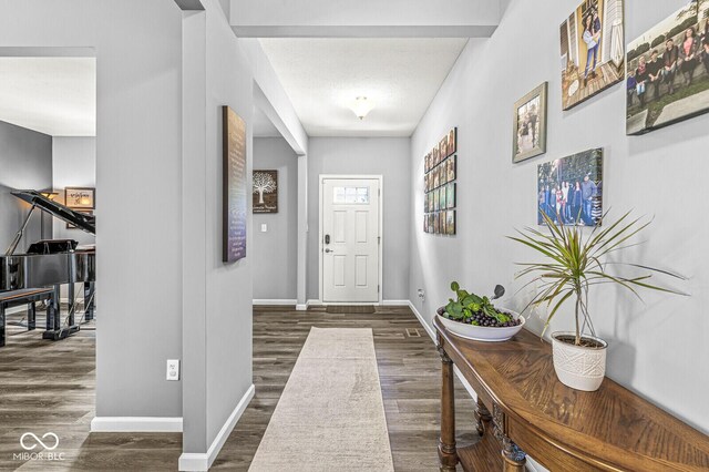 entrance foyer with dark wood-style flooring and baseboards
