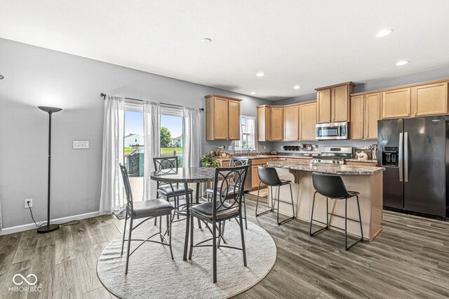 kitchen featuring stainless steel appliances, a center island, dark wood-style floors, a breakfast bar, and recessed lighting