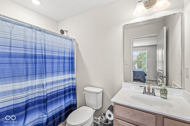 ensuite bathroom featuring vanity, toilet, and curtained shower