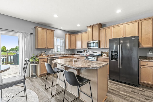 kitchen featuring stainless steel appliances, a kitchen breakfast bar, light wood-style flooring, a center island, and recessed lighting