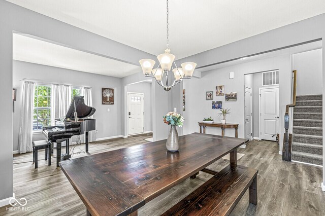 dining area with wood finished floors, a chandelier, stairs, and baseboards
