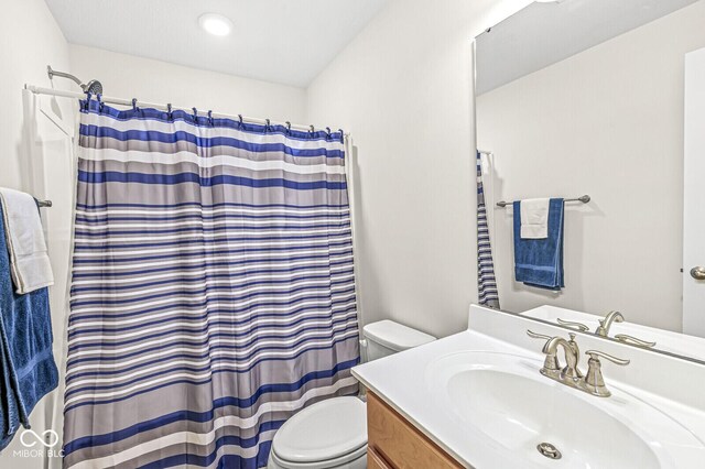 bathroom with toilet, vanity, and curtained shower