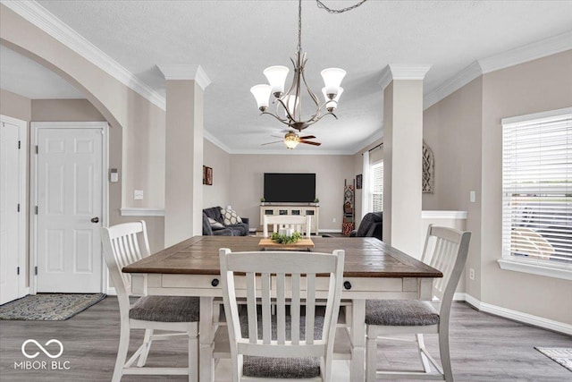 2434 Burgundy Way, Plainfield, IN 46168 - dining room featuring wood finished floors, a chandelier, arched walkways, baseboards, and crown molding