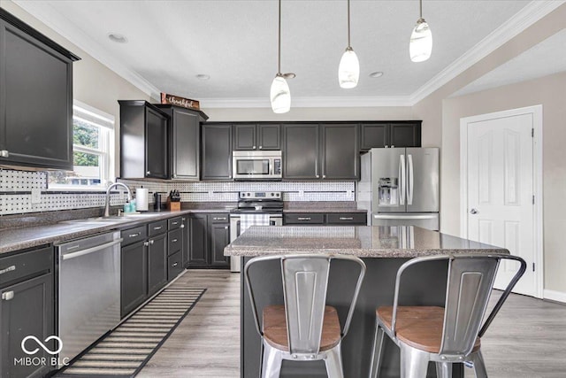 2434 Burgundy Way, Plainfield, IN 46168 - kitchen with stainless steel appliances, a center island, decorative backsplash, light wood-style floors, and ornamental molding