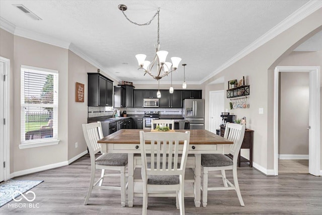 2434 Burgundy Way, Plainfield, IN 46168 - dining room featuring a chandelier, arched walkways, a textured ceiling, light wood finished floors, and baseboards