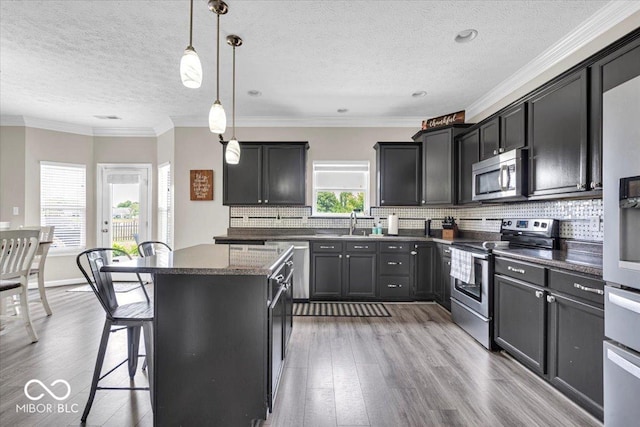 2434 Burgundy Way, Plainfield, IN 46168 - kitchen featuring stainless steel appliances, a kitchen island, light wood-type flooring, a textured ceiling, and a kitchen breakfast bar