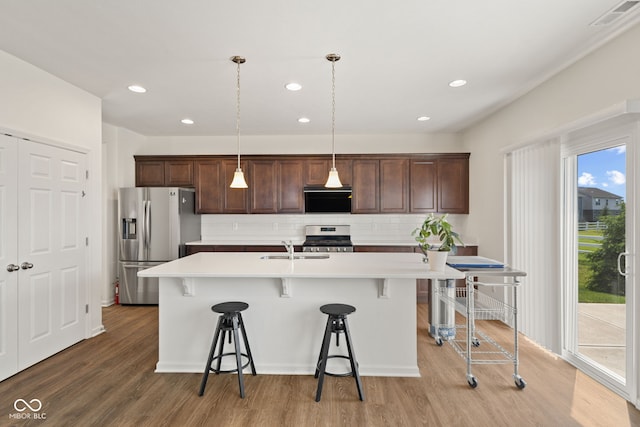 1026 Sorrell Pass, Greenwood, IN 46143 - kitchen with appliances with stainless steel finishes, ventilation hood, a breakfast bar area, backsplash, and recessed lighting