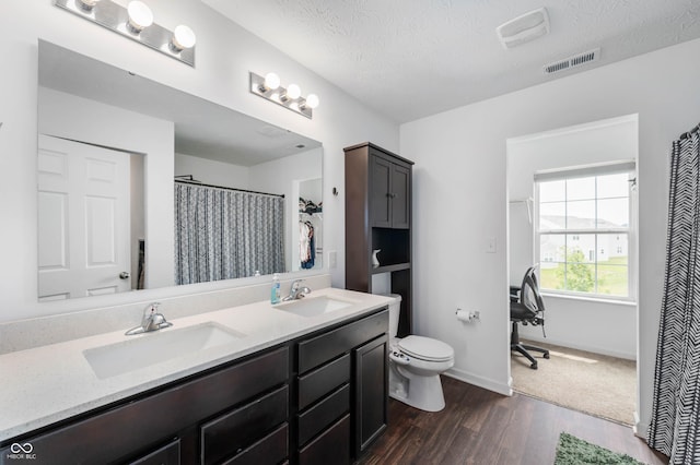 5794 Wintersweet Ln, Whitestown, IN 46075 - bathroom featuring toilet, double vanity, wood finished floors, baseboards, and a textured ceiling
