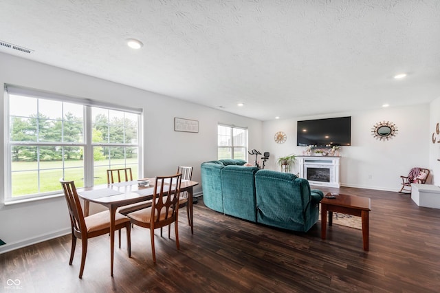 5794 Wintersweet Ln, Whitestown, IN 46075 - dining room with a textured ceiling, dark wood-style flooring, recessed lighting, a fireplace with raised hearth, and baseboards