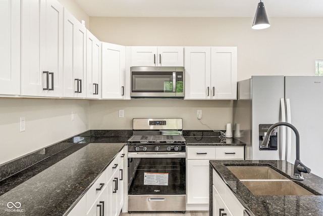 2427 N Rural St, Indianapolis, IN 46218 - kitchen featuring stainless steel appliances, white cabinetry, a sink, pendant lighting, and dark stone countertops
