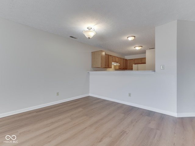 824 Ashton Park Dr, Greenwood, IN 46143 - kitchen featuring freestanding refrigerator, light wood-style flooring, a textured ceiling, baseboards, and under cabinet range hood