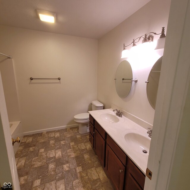 1306 W Daniel Dr, Greensburg, IN 47240 - full bath featuring double vanity, toilet, stone finish floors, tub / shower combination, and baseboards