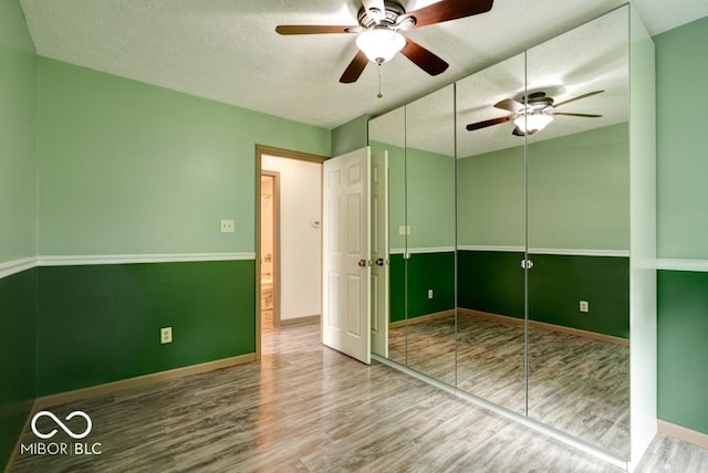 12157 Longstraw Dr, Indianapolis, IN 46236 - unfurnished bedroom featuring wood finished floors, a textured ceiling, baseboards, a closet, and a ceiling fan