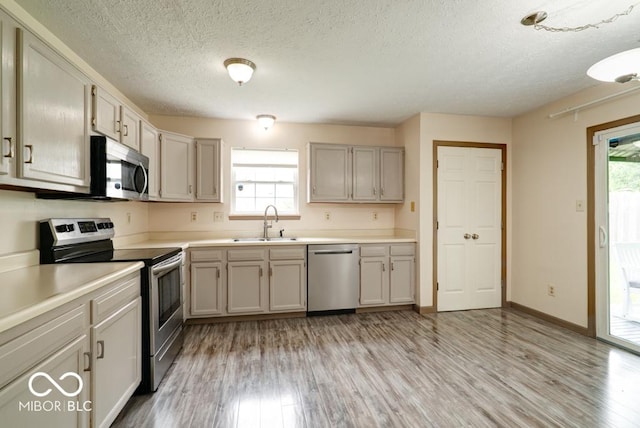 12157 Longstraw Dr, Indianapolis, IN 46236 - kitchen featuring appliances with stainless steel finishes, a sink, light wood-style flooring, a textured ceiling, and light countertops