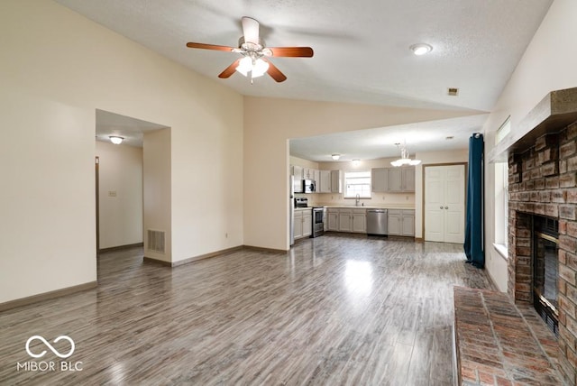 12157 Longstraw Dr, Indianapolis, IN 46236 - unfurnished living room featuring lofted ceiling, a fireplace, ceiling fan, a sink, and wood finished floors