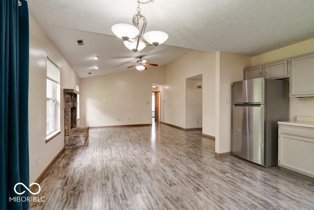 12157 Longstraw Dr, Indianapolis, IN 46236 - unfurnished living room with a chandelier, light wood finished floors, a textured ceiling, lofted ceiling, and a ceiling fan