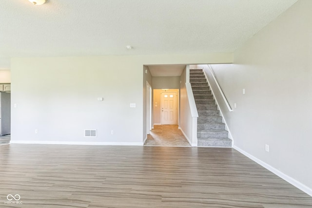 9692 Centennial Ct, Avon, IN 46123 - unfurnished living room with wood finished floors, baseboards, a textured ceiling, and stairs