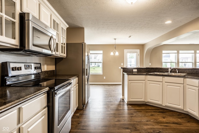 6114 Pebblebrooke Rd, Whitestown, IN 46075 - kitchen with stainless steel appliances, a sink, dark countertops, a textured ceiling, and dark wood-style floors