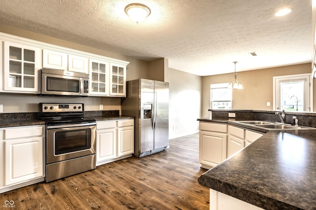 6114 Pebblebrooke Rd, Whitestown, IN 46075 - kitchen with stainless steel appliances, a sink, dark wood-style floors, dark countertops, and a textured ceiling