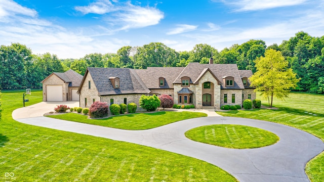 4181 Whitetail Woods Dr, Bargersville, IN 46106 - french country home with stone siding, curved driveway, a front lawn, and a chimney