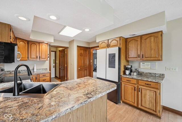 6983 White Oak Dr, Avon, IN 46123 - kitchen with white fridge with ice dispenser, a sink, stainless steel microwave, light wood-type flooring, and baseboards