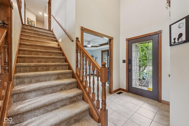 6983 White Oak Dr, Avon, IN 46123 - foyer with baseboards, light tile patterned floors, stairs, a towering ceiling, and a ceiling fan