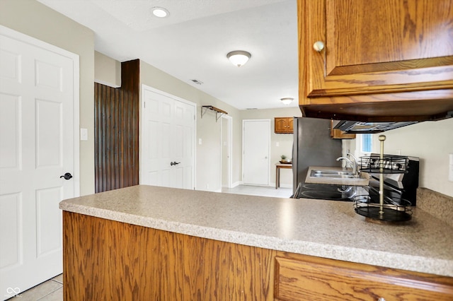 7430 Railway Ct, Indianapolis, IN 46256 - kitchen with brown cabinetry, a sink, a peninsula, light tile patterned flooring, and light countertops