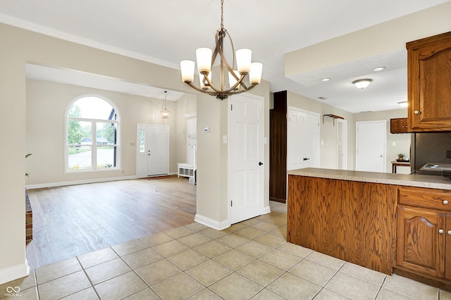 7430 Railway Ct, Indianapolis, IN 46256 - kitchen with light tile patterned flooring, light countertops, a chandelier, brown cabinets, and baseboards