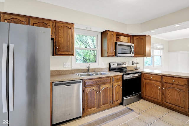 7430 Railway Ct, Indianapolis, IN 46256 - kitchen featuring appliances with stainless steel finishes, a sink, brown cabinets, light tile patterned flooring, and ornamental molding