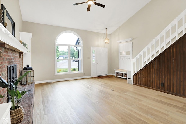 7430 Railway Ct, Indianapolis, IN 46256 - entryway featuring a ceiling fan, a brick fireplace, light wood finished floors, stairs, and high vaulted ceiling